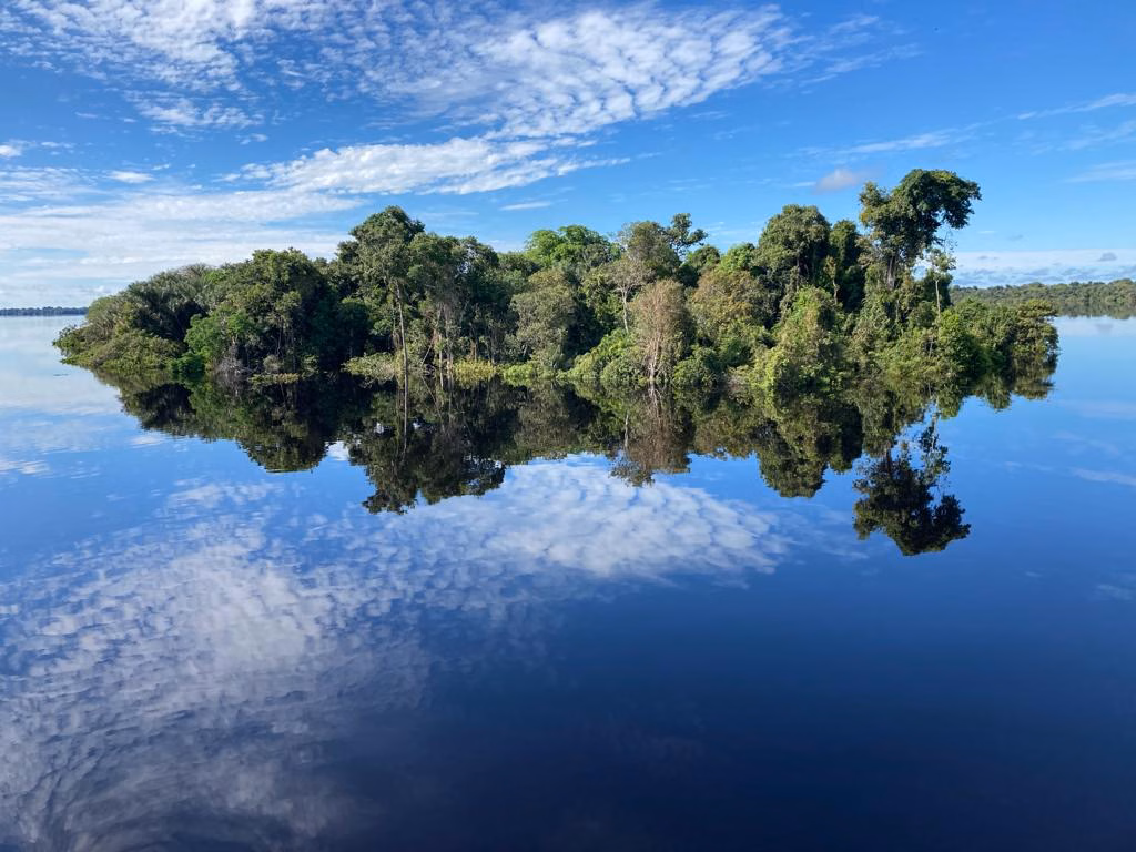 Ilha na Amazônia refletida no Rio Negro — acesso fluvial às comunidades ribeirinhas