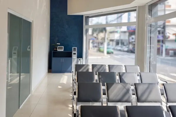 Sala de espera com poltronas junto à vitrine e parede azul ao fundo