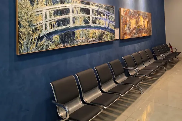 Fileira de poltronas sob duas reproduções de Claude Monet na parede azul
