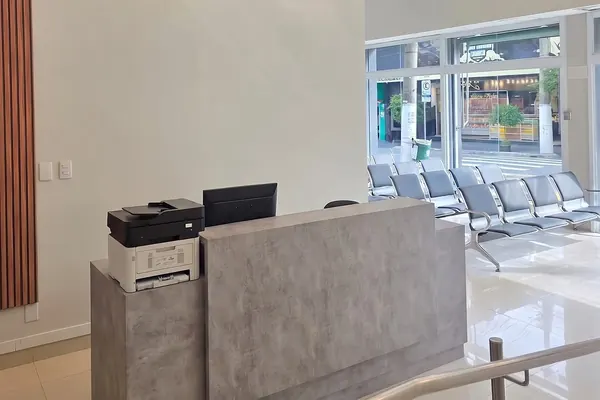 Balcão de recepção da clínica, com a sala de espera ao fundo