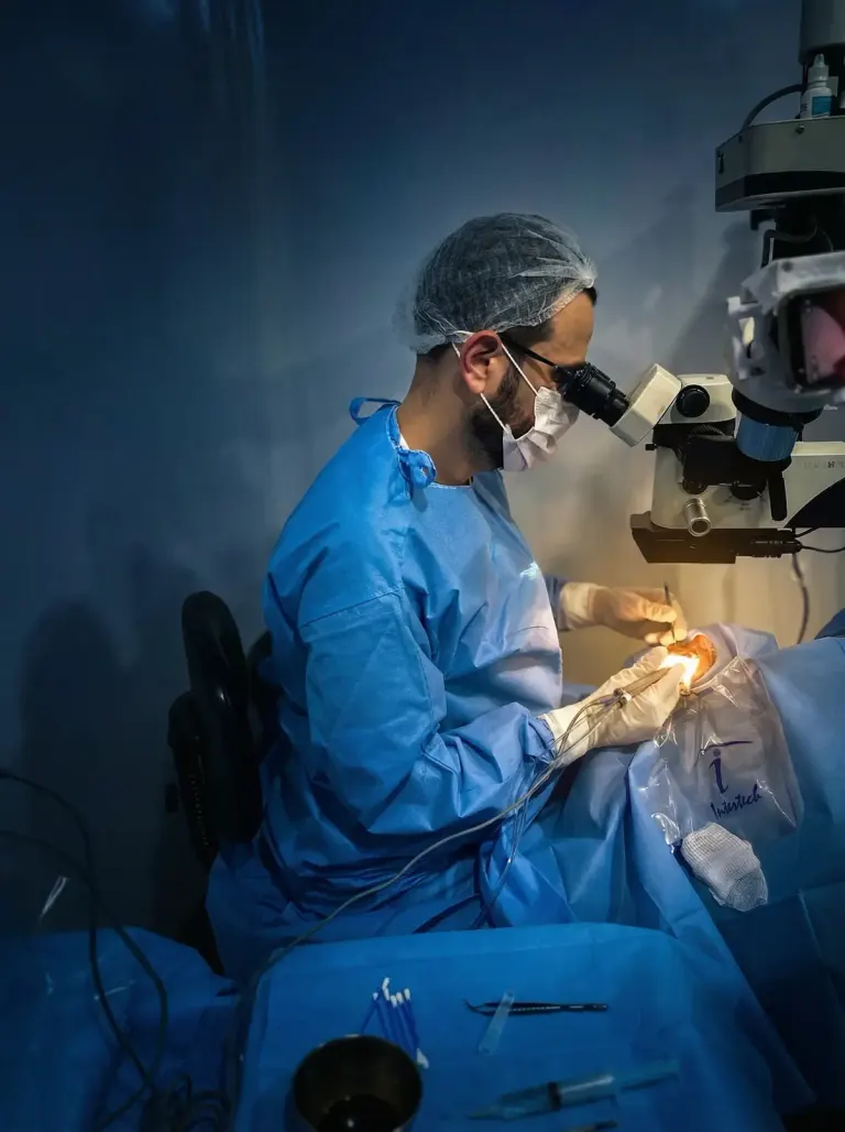 Dr. Fernando Drudi, de avental e touca cirúrgicos, operando ao microscópio