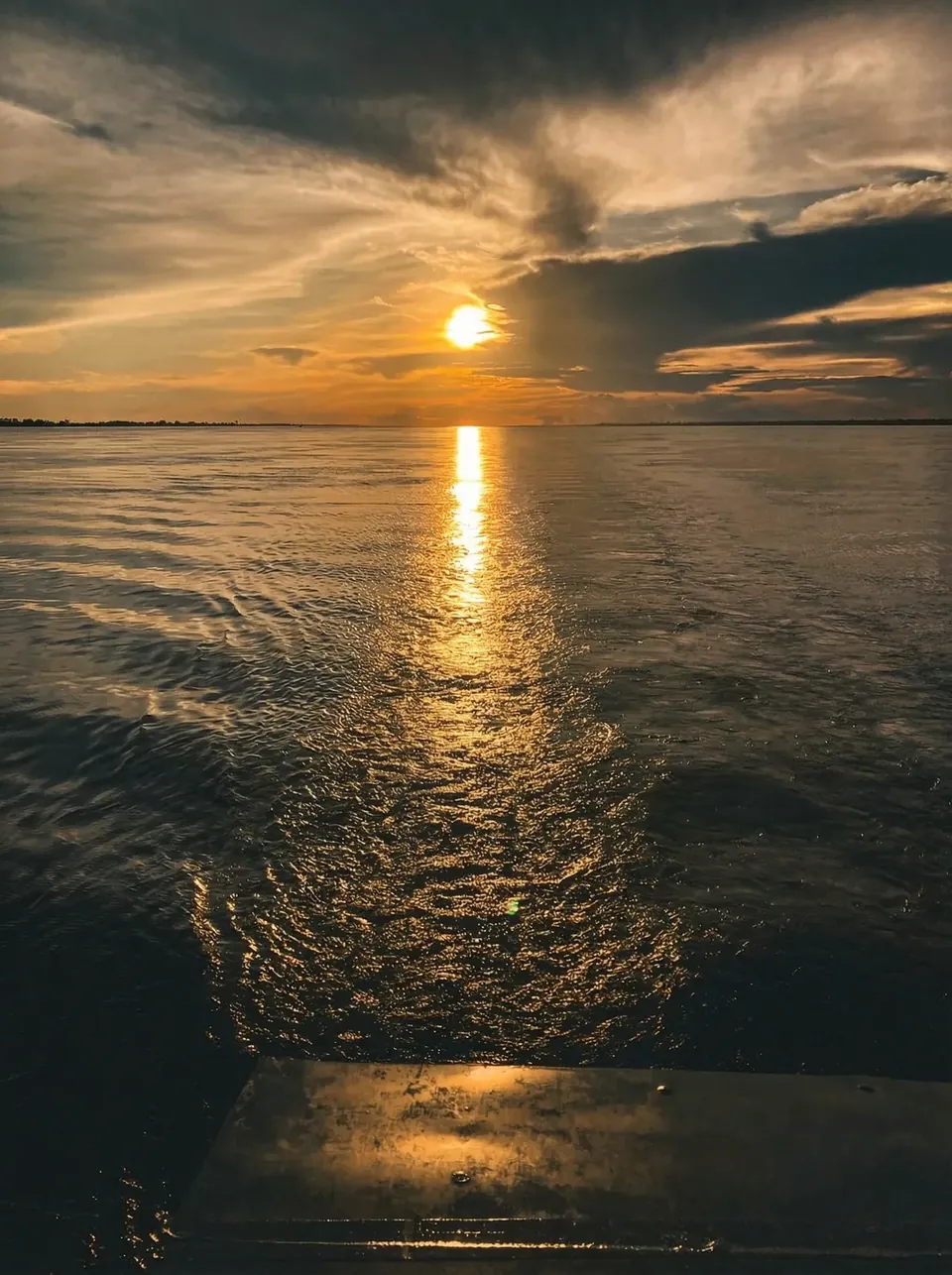 Pôr do sol sobre o rio, visto da popa de uma embarcação