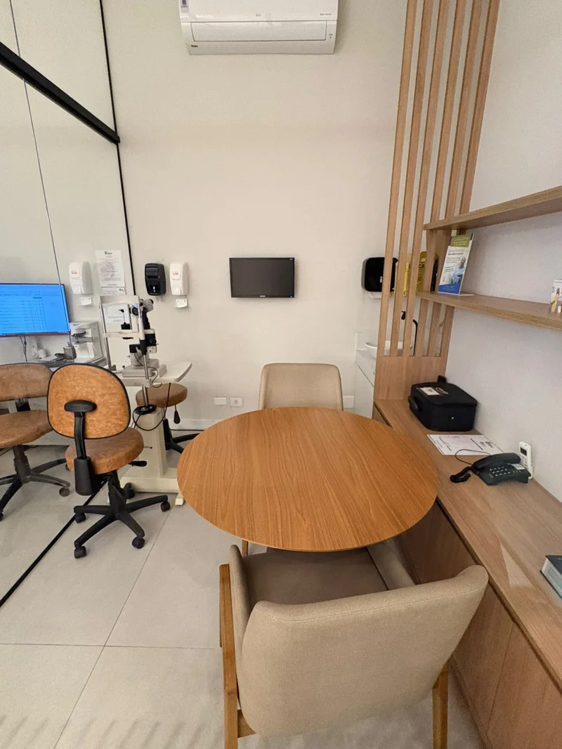 Consultório moderno MIRA Hospital Oftalmológico com equipamentos e mesa redonda