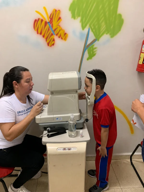Médica do Instituto Drudi e Almeida realizando triagem oftalmológica em criança no Instituto CNA