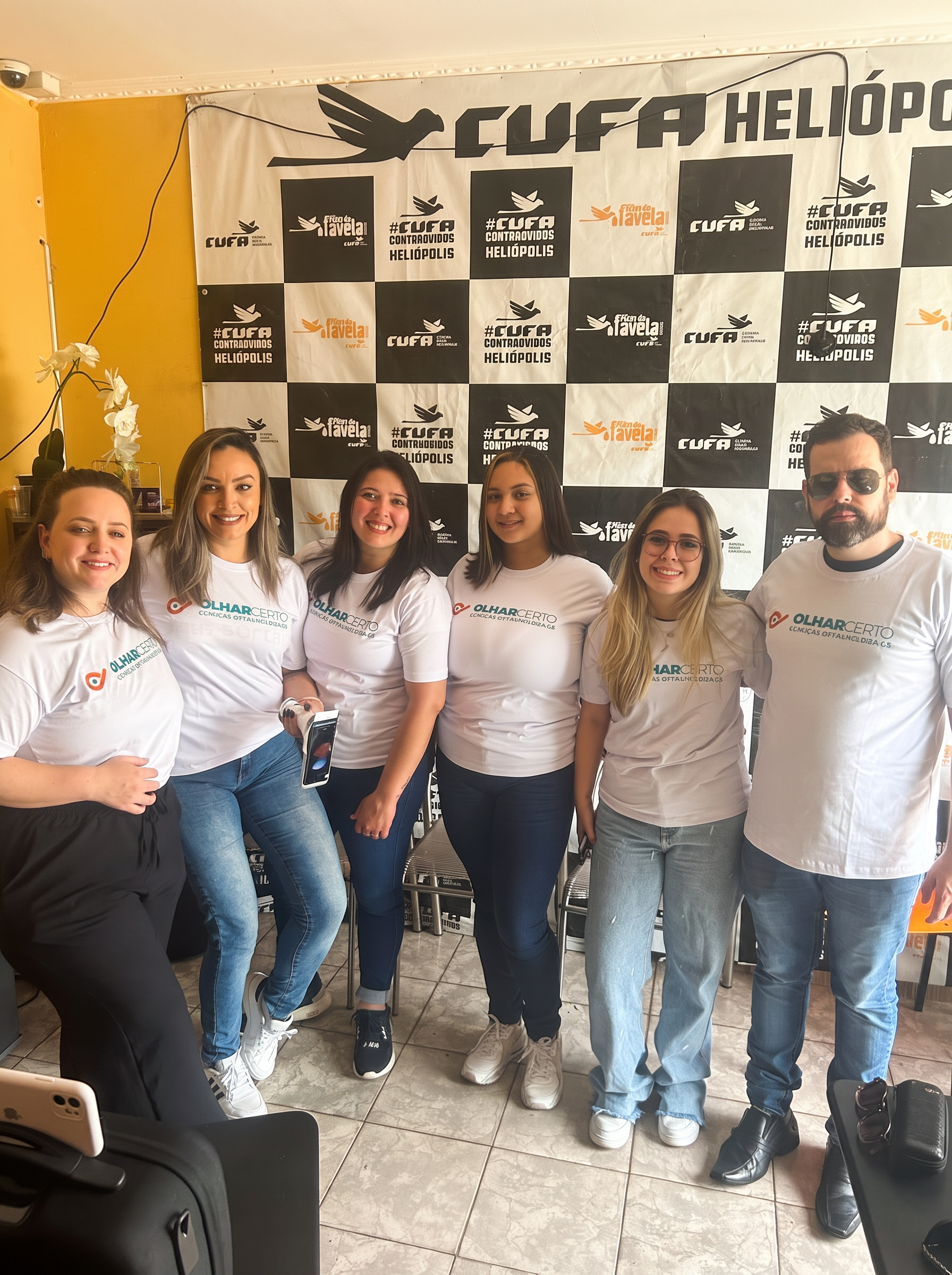 Equipe Olhar Certo na CUFA Heliópolis com backdrop da Central Única das Favelas