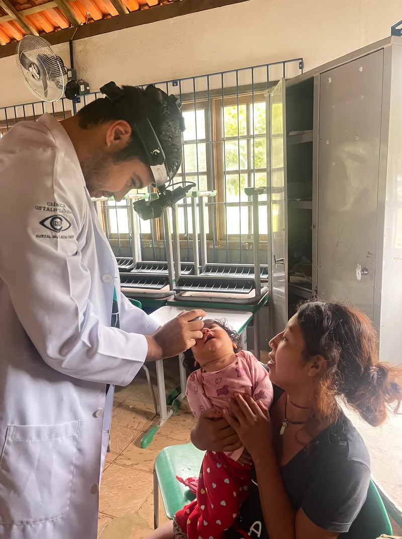 Médico oftalmologista examinando bebê indígena Guarani com oftalmoscópio na Terra Indígena Rio Silveira